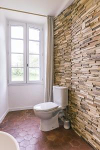 a bathroom with a toilet and a brick wall at Maison d'hôtes le Prieuré du Preux 