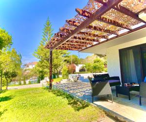 a patio with a table and chairs under a pergola at Villa Naya by the Beach in Anavyssos