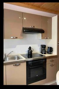 a kitchen with a sink and a stove top oven at Apt 1er étage Chalet Au coteau des xette in Gérardmer