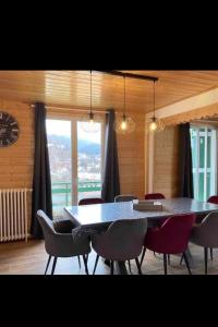a dining room with a table and chairs and a clock at Apt 1er étage Chalet Au coteau des xette in Gérardmer