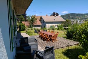 een houten terras met een tafel en stoelen op een huis bij Apt RDC Au coteau des xettes in Gérardmer