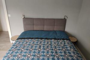 a bed with a blue and white quilt on it at Apt RDC Au coteau des xettes in Gérardmer
