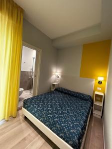 a bedroom with a bed and a yellow curtain at Hotel Sissi in Rimini