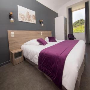 a bedroom with a large bed with a purple blanket at HOSTELLERIE CHARLES de FOUCAULD in Viviers