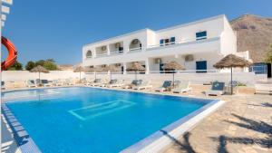 a resort with a swimming pool and chairs and a building at Petit Homme by Andreas in Perissa