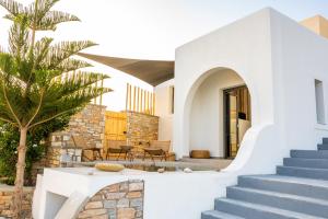 a white house with a palm tree and stairs at Ios Seaside house with sunset view and small pool in Ios Chora