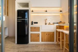 a kitchen with a black refrigerator and wooden cabinets at Ios Seaside house with sunset view and small pool in Ios Chora