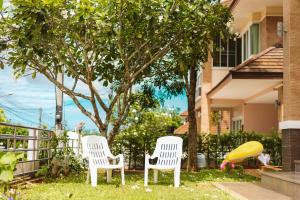 two white chairs sitting in the grass in front of a house at June Pool Villa in Krabi