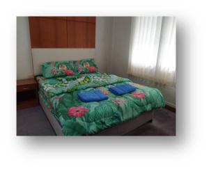 1 dormitorio con 1 cama con flores y almohadas azules en ศูนย์ฝึกอบรมสวนสัตว์เปิดเขาเขียว JJJ, 