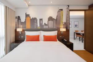 a bedroom with a large bed with orange pillows at Citadines Benavidez Makati in Manila