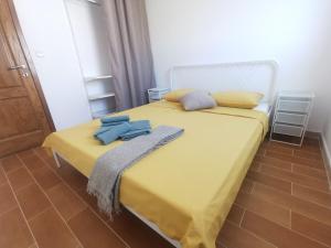 a yellow bed with two towels on top of it at Apartmani Lešić Tribunj in Tribunj
