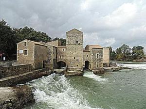 um velho edifício de pedra no meio de um rio em L'OUSTAL DE FLO em Florensac