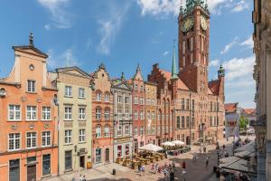 a group of buildings with a clock tower at Downtown Apartments Old Town Pure White in Gdańsk