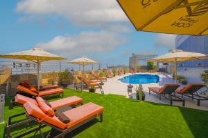 eine Terrasse mit Stühlen und Sonnenschirmen neben einem Pool in der Unterkunft Icon Delux Hotel Apartments Al Barsha - Formerly Abidos in Dubai