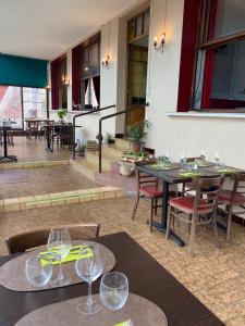 un restaurante con mesas y sillas y copas de vino. en Hôtel Les trois maures, en Verdun-sur-le-Doubs