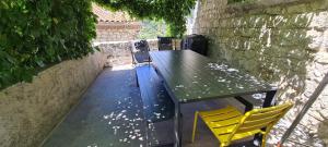 a green table and two yellow chairs on a patio at Magnifique maison en coeur de Balazuc, proche plages ardèche in Balazuc