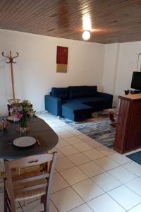 ein Wohnzimmer mit einem blauen Sofa und einem Tisch in der Unterkunft Appartement entier, La Chacuniere in Saint-Amant-Tallende