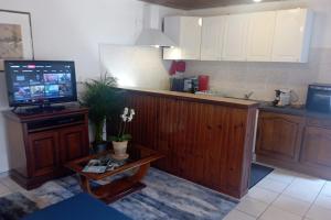 eine Küche mit einem TV auf einer Theke mit einem Tisch in der Unterkunft Appartement entier, La Chacuniere in Saint-Amant-Tallende