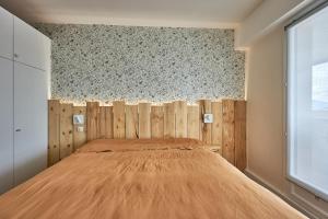 een slaapkamer met een bed met een houten hoofdeinde bij Le Tikahupo - Charmant appt vue sur le port in Courseulles-sur-Mer