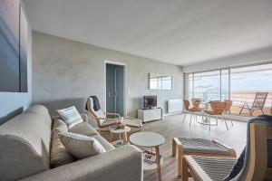 een woonkamer met een bank en tafels en stoelen bij Le Tikahupo - Charmant appt vue sur le port in Courseulles-sur-Mer