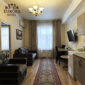 sala de estar con sofá, mesa y cocina en Europa Hotel, en Uralsk
