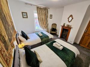 a bedroom with two beds and a couch and a window at Cute Cottage in Egham Heathrow- 7 Guests 3 bedrooms in Egham