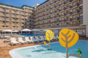 a hotel swimming pool with chairs and a building at htop Amatista #htopBliss in Lloret de Mar