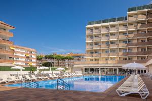 a hotel swimming pool with lounge chairs and a hotel at htop Amatista #htopBliss in Lloret de Mar