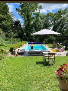 a swimming pool with an umbrella and a table and chairs at Le Marais des Littes in Chonas-lʼAmballan