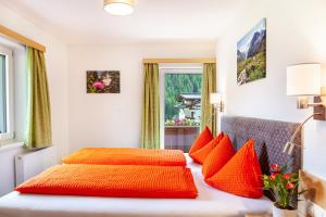 two beds with orange pillows in a bedroom at Haus Alpenheim Apartment 3 in Tux
