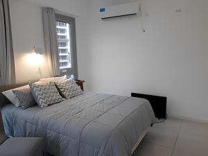a white bedroom with a large bed with a window at Estudio en Puerto Norte con PILETA incluida y COCHERA opcional in Rosario
