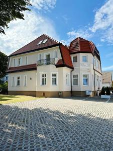 ein großes Haus mit rotem Dach auf einer Ziegelsteinfahrt in der Unterkunft Willa Słoneczna in Ustronie Morskie