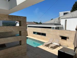 two chairs and a swimming pool on a house at Moradia Lux RR com piscina in Penafiel