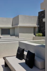 two black pillows sitting on a bench in front of a building at Alaso Design Suites in Fira