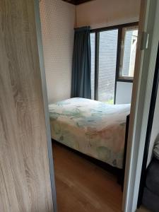 een kleine slaapkamer met een bed en een raam bij Uitrusthuisje in Erm