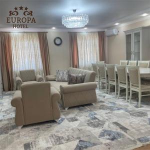 una sala de espera con sofás, mesa y sillas en Europa Hotel en Uralsk