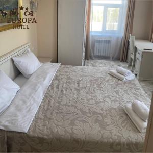 1 dormitorio con 1 cama grande y 2 toallas. en Europa Hotel, en Uralsk