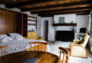 1 dormitorio con cama, mesa y chimenea en Maison des 4 Vallées, en La Barthe-de-Neste
