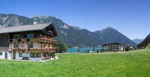 a building in a field with a lake and mountains at Landhaus Obertuschenhof in Pertisau