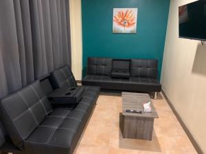 a living room with black leather couches and a table at Samoa Business Apartments 2 in Apia