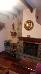 salon z kamiennym kominkiem i zegarem na ścianie w obiekcie Casa Rural La Huerta w mieście Riaño