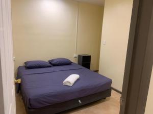 um quarto com uma cama com lençóis roxos e uma almofada branca em Samoa Business Apartments 2 em Apia