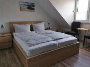 a bed with white sheets and pillows in a room at Ferienhaus Rosenboom Rosenboom 02 in Norderney