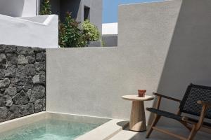 a patio with a small table and a chair at Alaso Design Suites in Fira