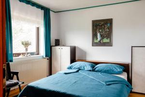 sypialnia z łóżkiem z niebieską pościelą i oknem w obiekcie Green Point w mieście Preserje