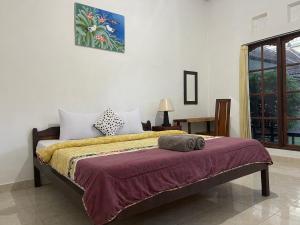 a bedroom with a bed with a purple blanket at Shipwreck Point Inn in Nusa Lembongan