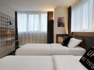 a hotel room with two beds and a window at Moxy Belgrade in Belgrade