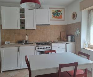 uma cozinha com armários brancos e uma mesa com cadeiras em Casa Vanna em Mezzano