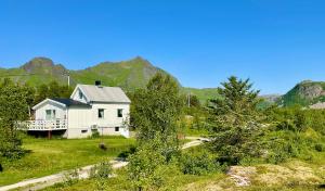 a white house in a field with mountains in the background at Fishermans Paradise Lofoten in Leknes