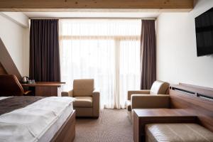 um quarto de hotel com uma cama e uma cadeira e uma janela em Pension Tatrasport Zampa em Starý Smokovec